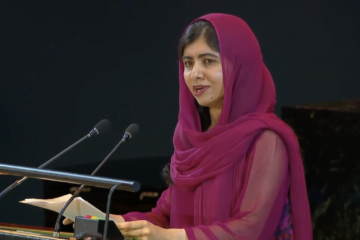 Malala Yousafzai, at the UN podium, in a dark red head scarf, stresses urgency and benefit of universal access to education.