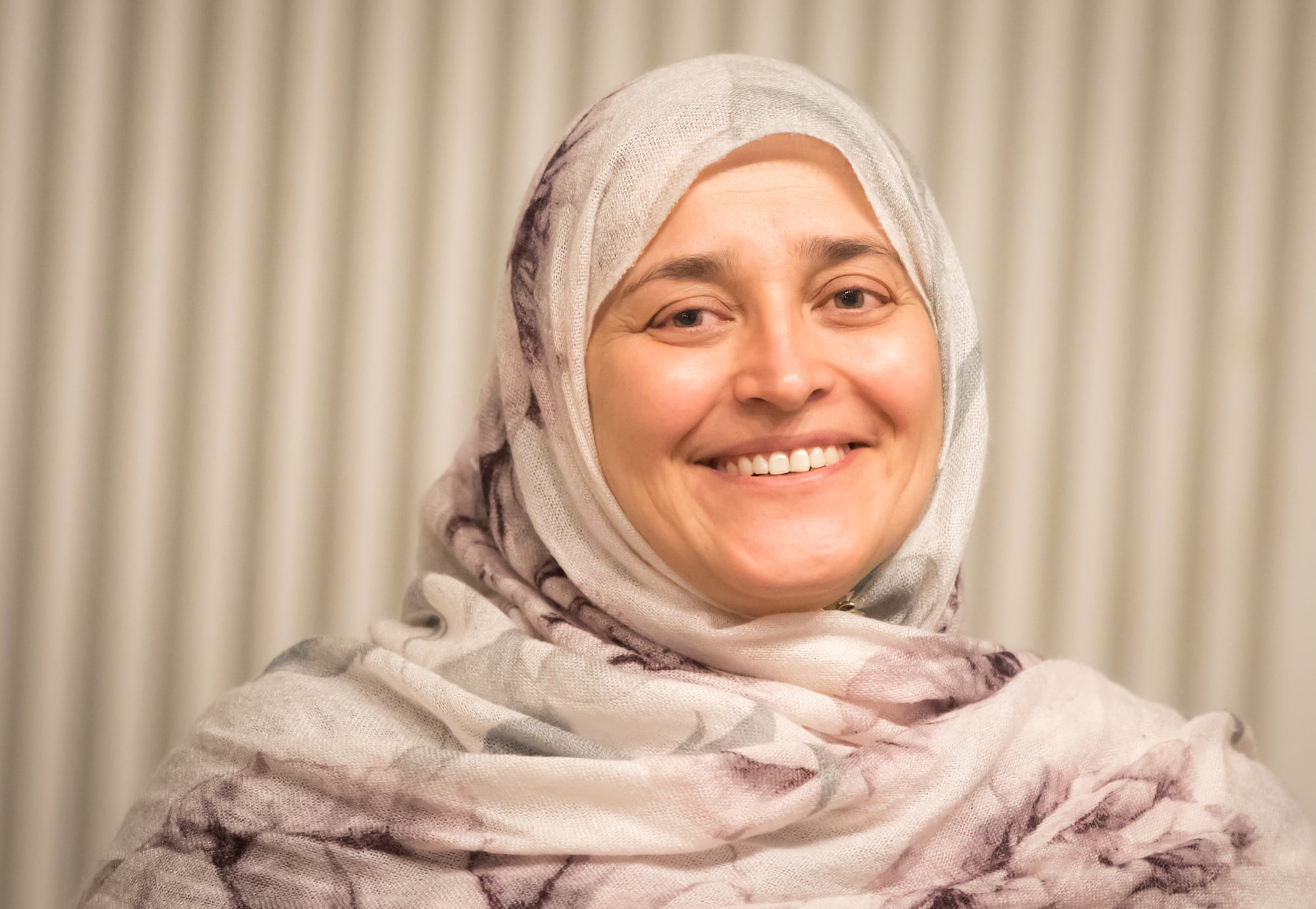 Jamila Afghani, NGO NECDO founder, and Aurora Prize winner smiles broadly in a traditional head scarf.