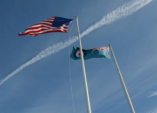 US Flag and the United Kingdom fly together over a backdrop of a jet exhaust trail.